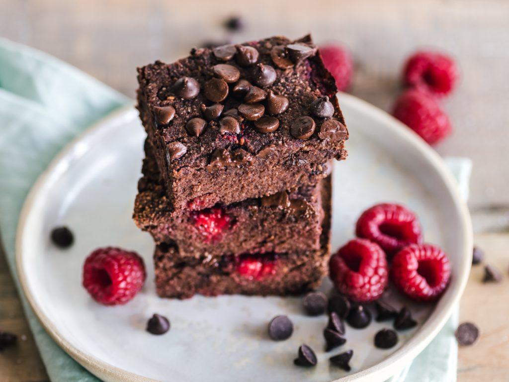 A stack of brownies with raspberries and chocolate chips