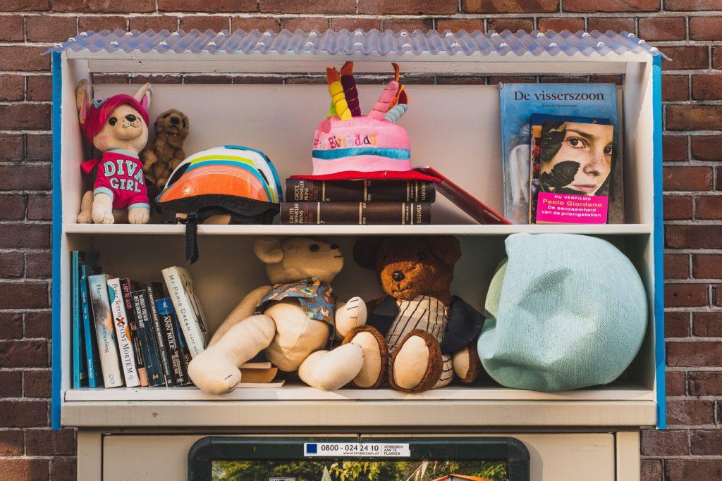 Two shelves of books and vintage toys against a brick wall.